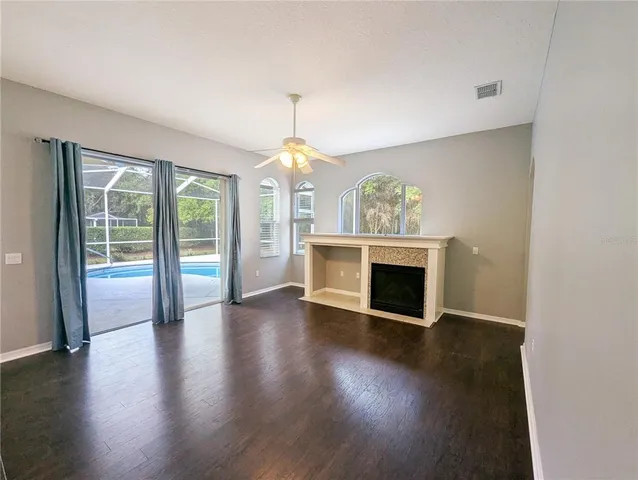 an empty room with wooden floor fireplace and windows