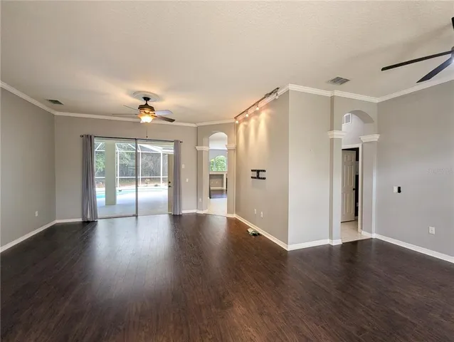 a view of an empty room with a window and wooden floor
