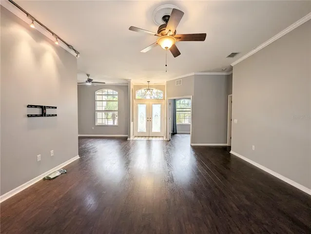 an empty room with wooden floor fan and windows