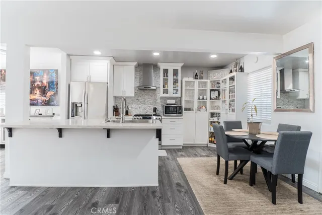 a kitchen with stainless steel appliances kitchen island granite countertop a table chairs sink and cabinets