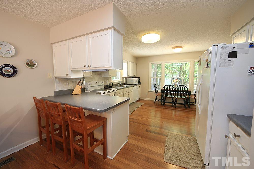 1295 Pilot-Riley Road Zebulon, NC 27597 - Photo 4 of 18 a kitchen with stainless steel appliances granite countertop a stove a refrigerator a kitchen island a dining table and chairs with wooden floor