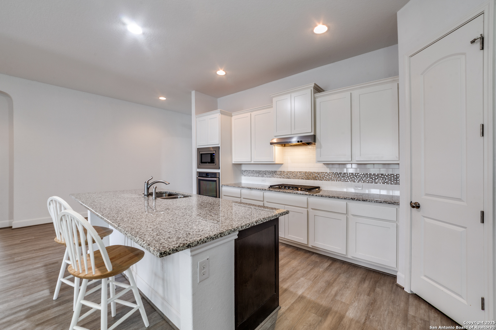 836 Silver Fox Cibolo, TX 78108 - Photo 9 of 26 a kitchen with stainless steel appliances granite countertop a stove top oven a sink and white cabinets with wooden floor