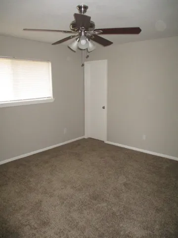 a view of a room with a ceiling fan and carpet