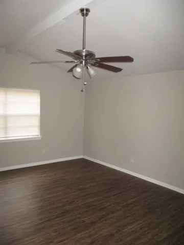 a view of a room with wooden floor a ceiling fan and window