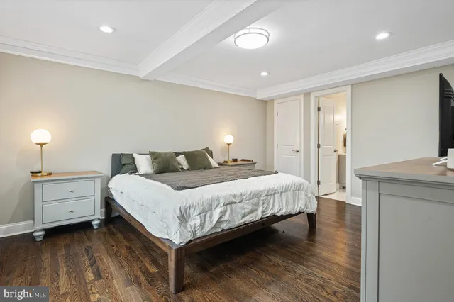 a bedroom with a bed and a flat tv screen on dresser