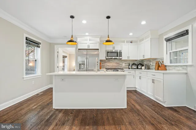 a kitchen with a sink dishwasher a stove and a dining table with wooden floor