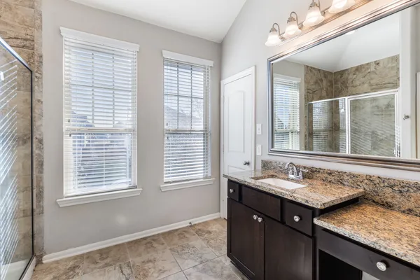 an empty room with chandelier fan and windows