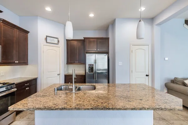 a large kitchen with stainless steel appliances kitchen island granite countertop a refrigerator oven a sink dishwasher a dining table and chairs with wooden floor