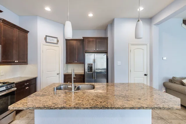 a large kitchen with stainless steel appliances kitchen island granite countertop a refrigerator oven a sink dishwasher a dining table and chairs with wooden floor