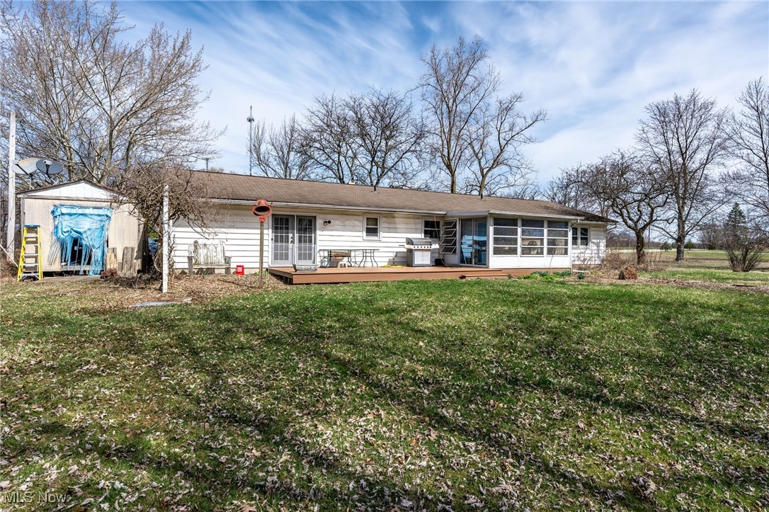 4790 Paradise Road Seville, OH 44273 - Photo 10 of 45 Rear view of property featuring a sunroom, a storage shed, a deck, an outbuilding, and a yard