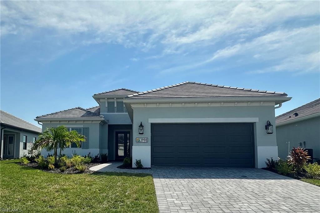 3998 Perseus Street Naples, FL 34120 - Photo 1 of 26 Prairie-style home featuring a tiled roof, a front yard, decorative driveway, stucco siding, and a garage