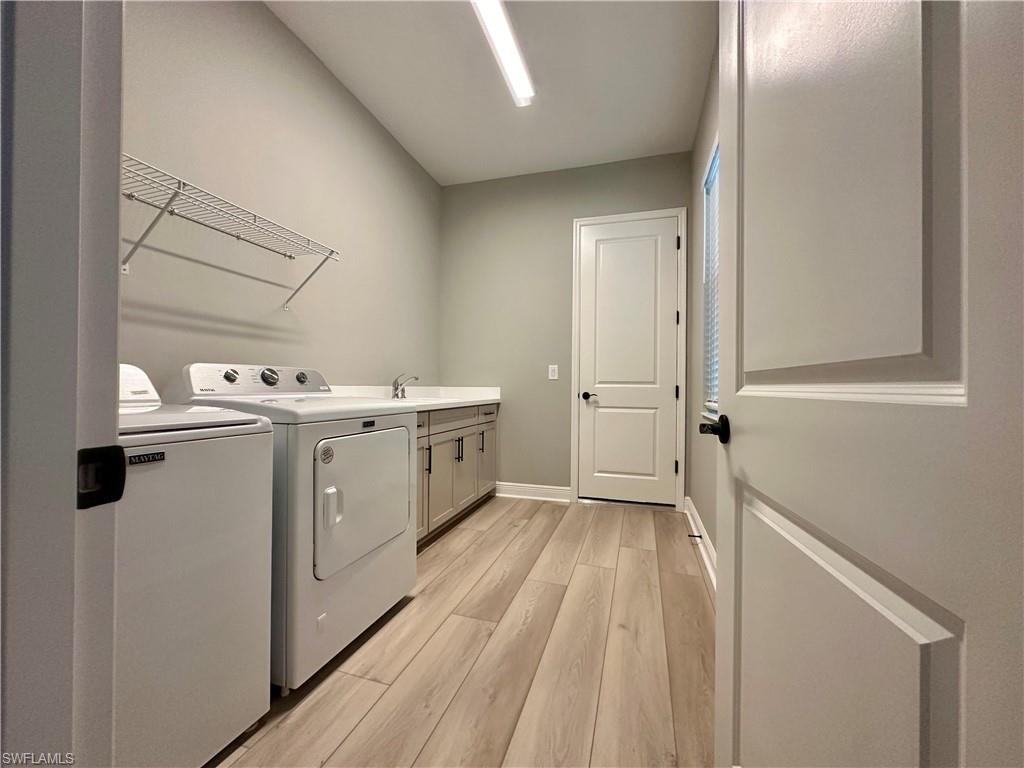 3998 Perseus Street Naples, FL 34120 - Photo 14 of 26 Washroom featuring washer and clothes dryer, light wood-style flooring, and cabinet space
