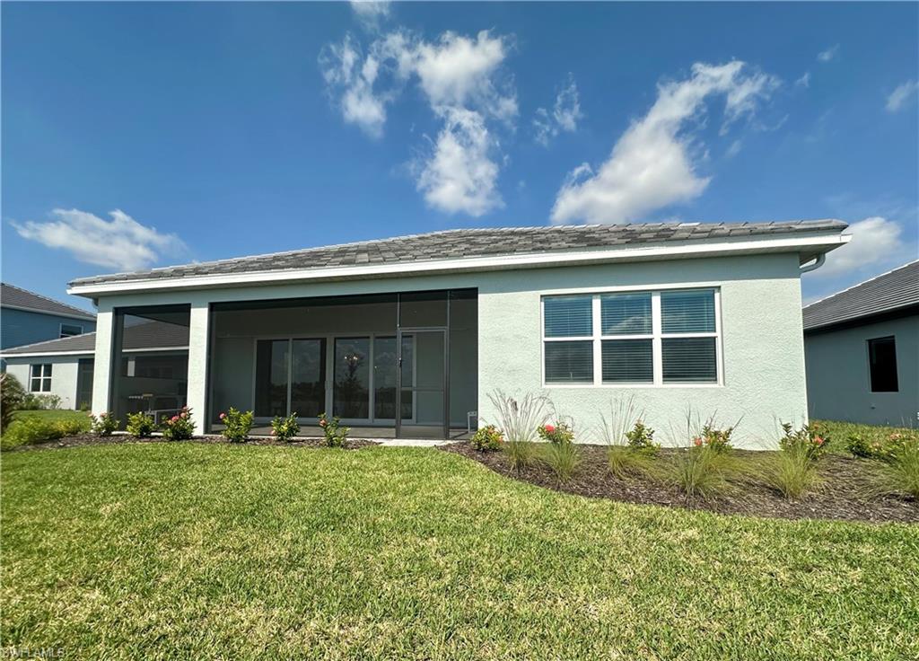 3998 Perseus Street Naples, FL 34120 - Photo 17 of 26 Back of property featuring stucco siding, a yard, and a sunroom