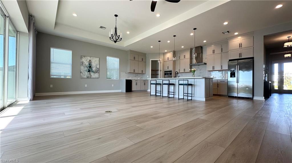 3998 Perseus Street Naples, FL 34120 - Photo 3 of 26 Kitchen featuring appliances with stainless steel finishes, light countertops, a kitchen breakfast bar, backsplash, and recessed lighting