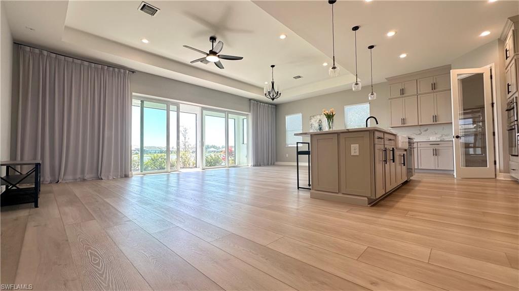 3998 Perseus Street Naples, FL 34120 - Photo 26 of 26 Kitchen with a kitchen bar, a raised ceiling, open floor plan, light wood-style flooring, and recessed lighting