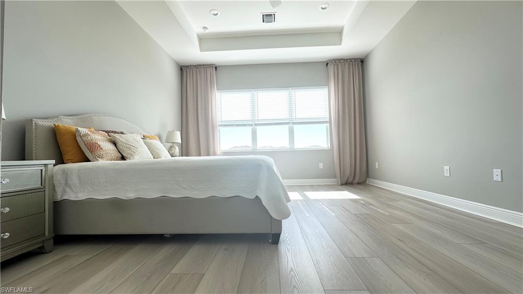 3998 Perseus Street Naples, FL 34120 - Photo 6 of 26 Bedroom with a raised ceiling and light wood finished floors