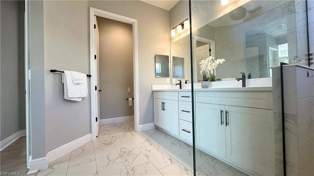 3998 Perseus Street Naples, FL 34120 - Photo 8 of 26 Bathroom with light marble finish floors, double vanity, and a stall shower