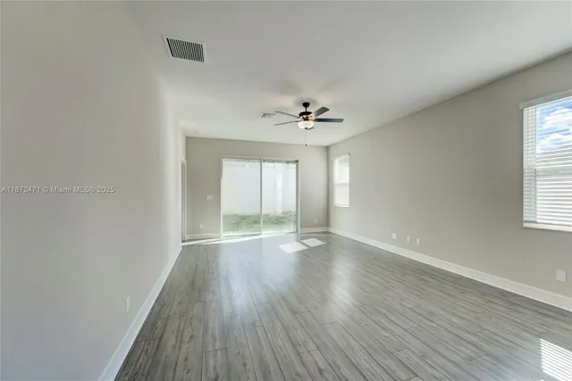a view of an empty room with a window and wooden floor