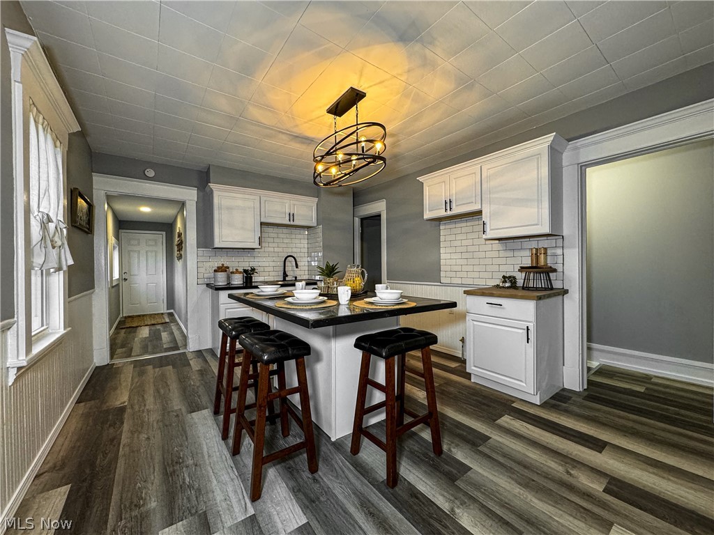 306 Robinson Road Campbell, OH 44405 - Photo 6 of 21 Kitchen featuring dark hardwood / wood-style flooring, white cabinets, a kitchen breakfast bar, and a chandelier