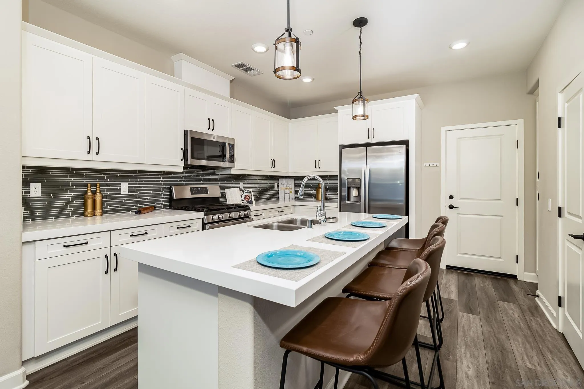 1094 Delpy View Point Vista, CA 92084 - Photo 6 of 43 a kitchen with kitchen island granite countertop a sink a stove a refrigerator and white cabinets