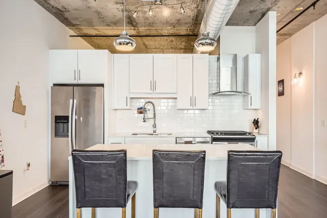 a kitchen with a refrigerator a stove a sink and white cabinets with wooden floor