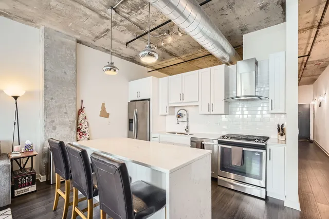 a kitchen with stainless steel appliances a stove a refrigerator and a dining table