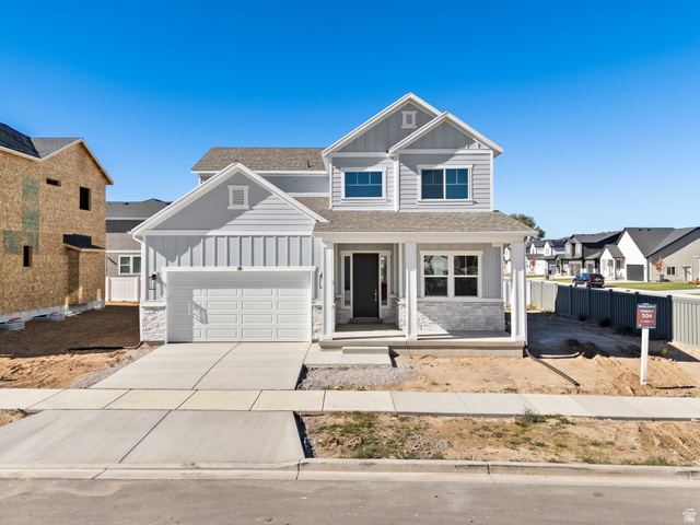 18 South Crimson Way, Unit 304 Mapleton, UT 84664 - Photo 1 of 17 View of front facade featuring board and batten siding, covered porch, stone siding, concrete driveway, and a shingled roof