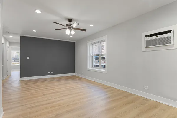 a view of an empty room with a window and wooden floor