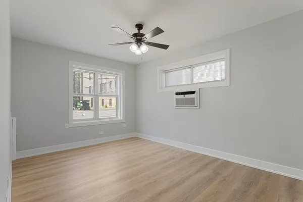 a view of empty room with wooden floor and fan
