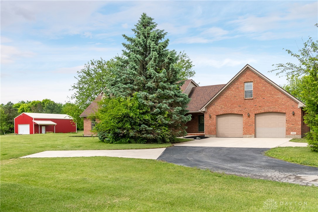9981 Ridge Acres Lane Englewood, OH 45322 - Photo 4 of 73 This classic brick residence features an attached garage and a striking red barn, creating an inviting facade.