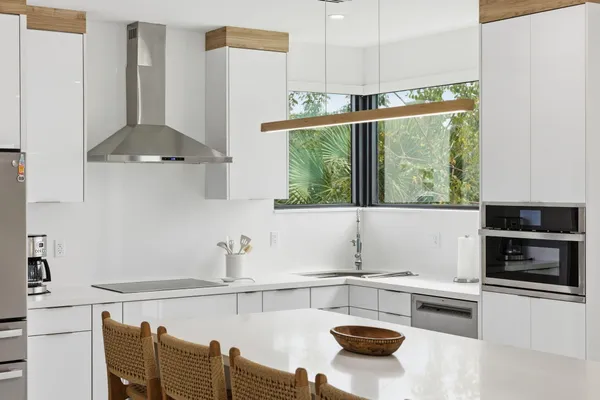 a kitchen with stainless steel appliances granite countertop a refrigerator a stove a sink dishwasher and white cabinets with wooden floor