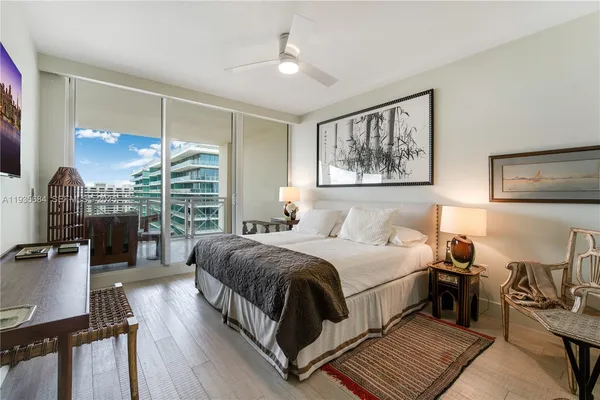 a bedroom with bed a mirror and a large window