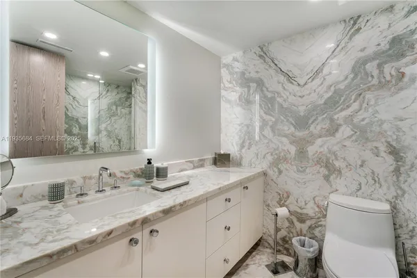 a bathroom with a granite countertop sink mirror and toilet