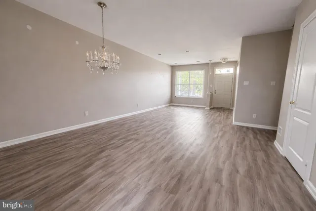 a view of empty room with wooden floor and window