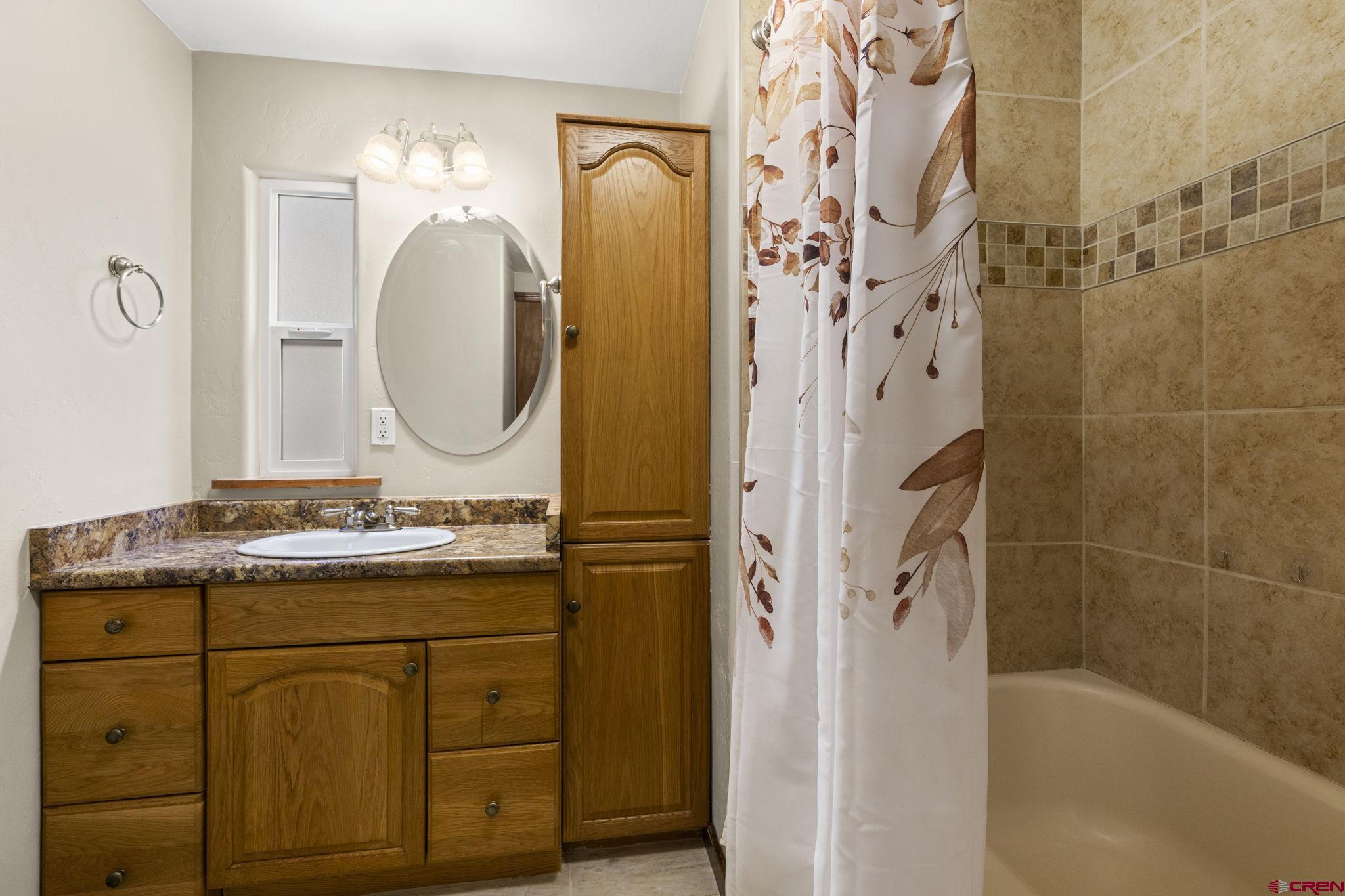 564 Spring Road Durango, CO 81303 - Photo 13 of 45 a bathroom with a granite countertop sink a mirror a vanity and a shower