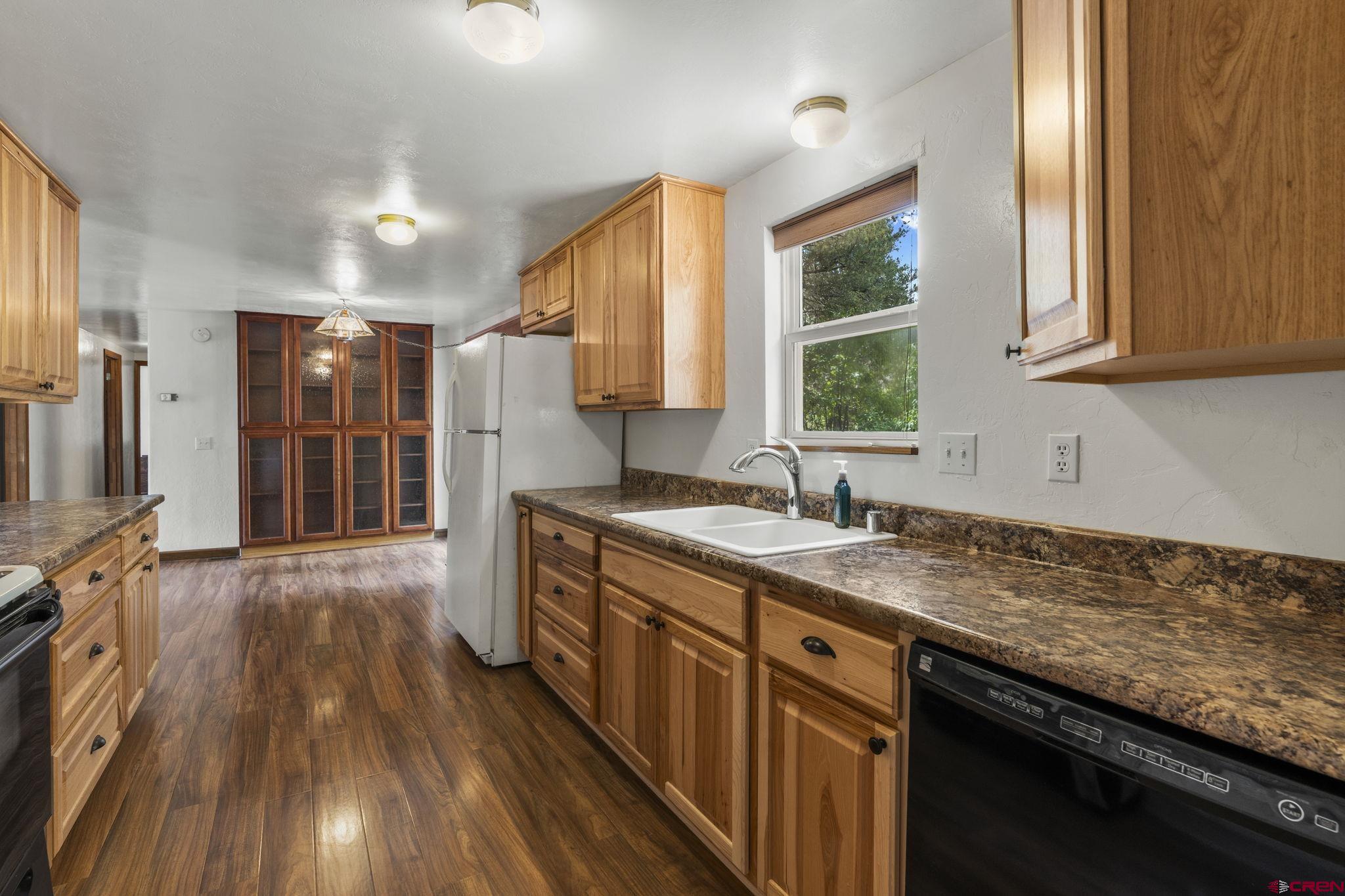 564 Spring Road Durango, CO 81303 - Photo 10 of 45 a kitchen with wooden floors wooden cabinets a sink and a window