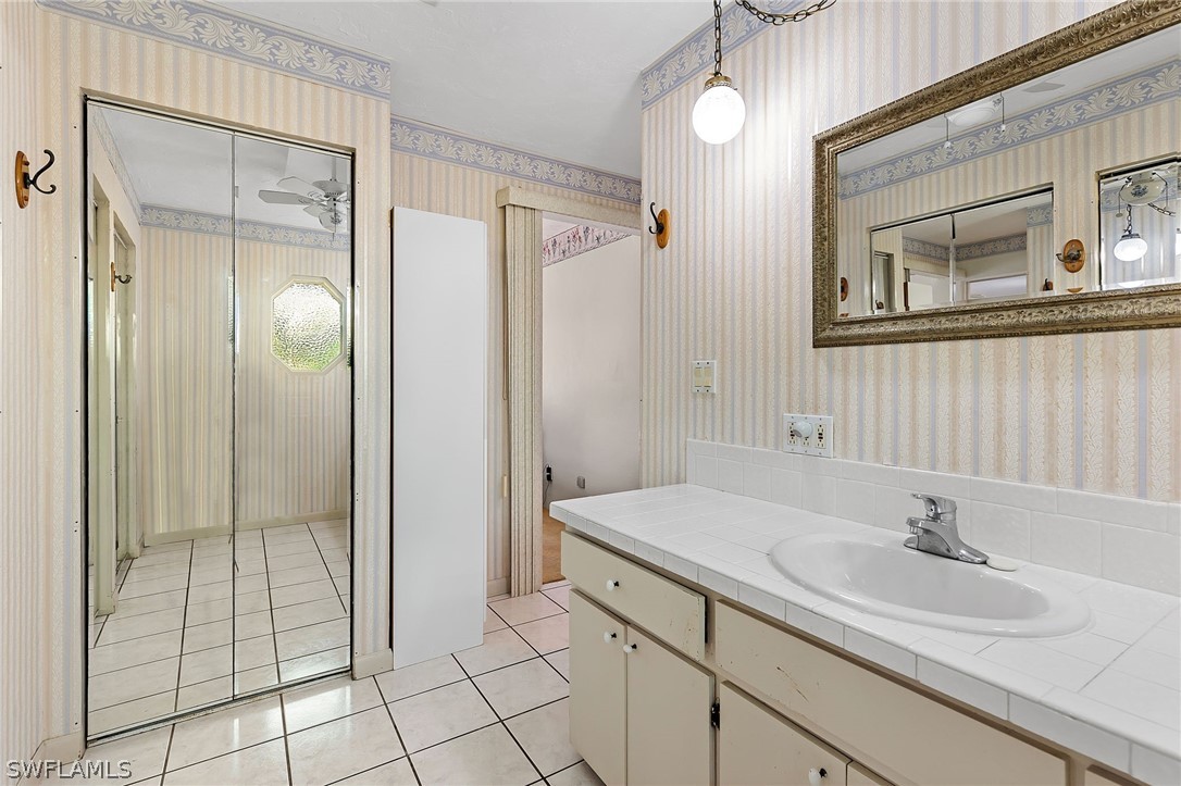 17501 Laurel Valley Road Fort Myers, FL 33967 - Photo 21 of 26 a bathroom with a granite countertop sink a mirror and a shower
