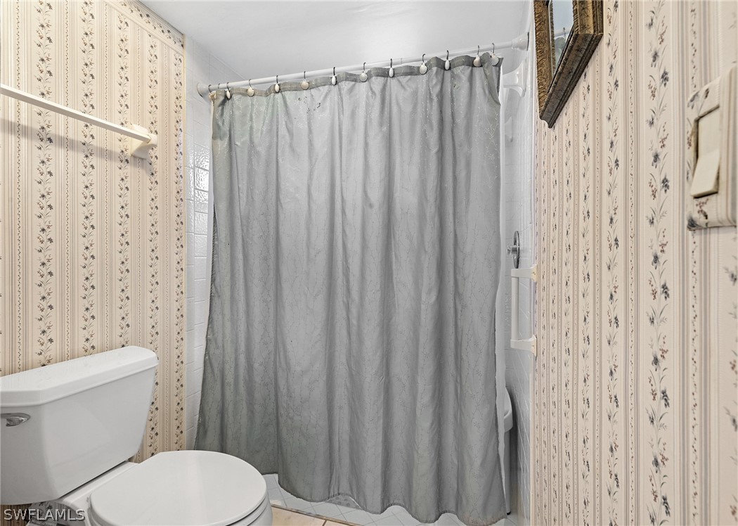 17501 Laurel Valley Road Fort Myers, FL 33967 - Photo 22 of 26 a white toilet sitting next to a shower curtain