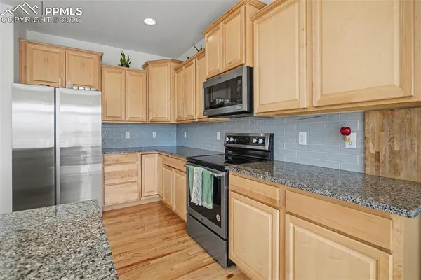 a kitchen with stainless steel appliances granite countertop a stove a sink and a refrigerator