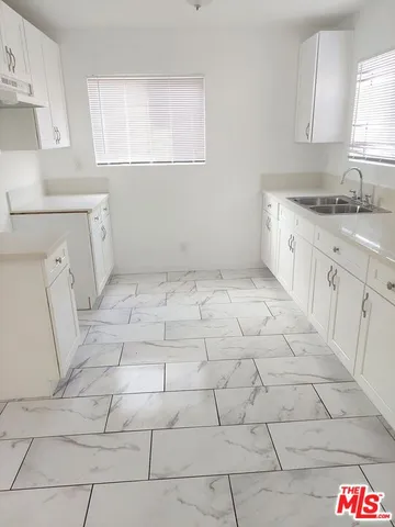 a kitchen with a sink a stove a window and cabinets