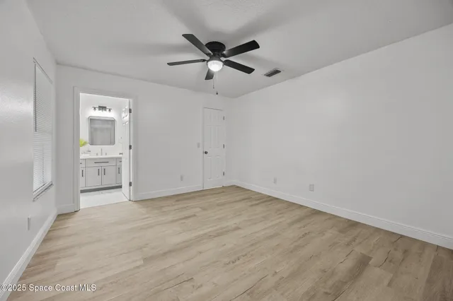 an empty room with a window and a ceiling fan