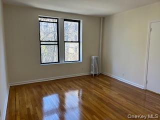 83-52 Talbot Street, Unit 3J Queens, NY 11415 - Photo 21 of 50 an empty room with wooden floor and windows