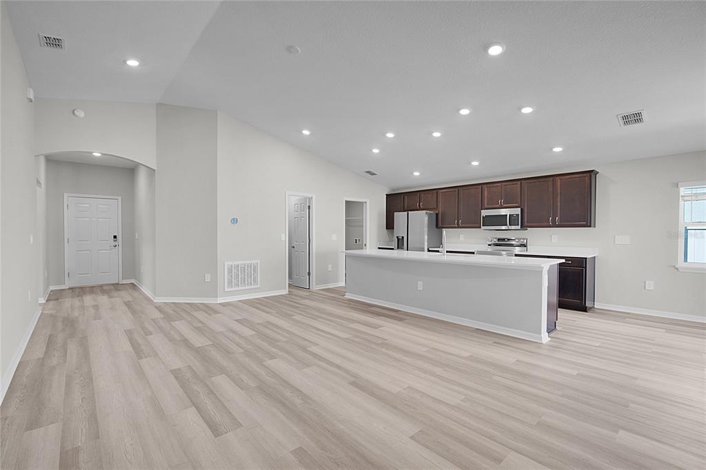 1617 Astrid Road Davenport, FL 33837 - Photo 18 of 43 a open kitchen with kitchen island a sink dishwasher a refrigerator and white cabinets with wooden floor