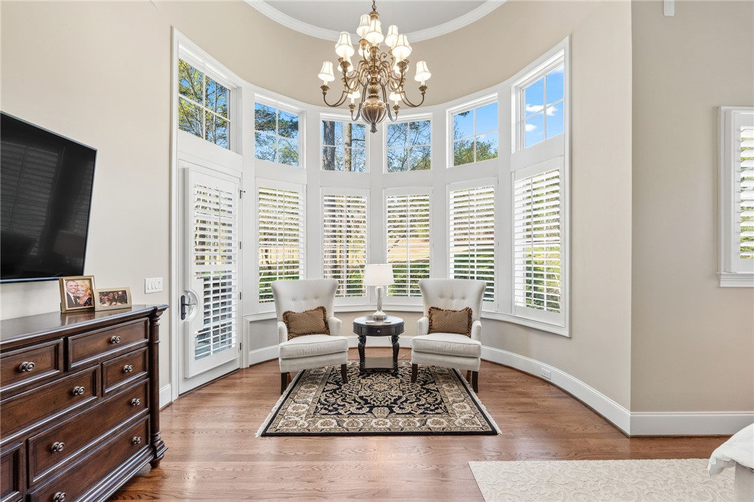 418 Augusta Way Sunset, SC 29685 - Photo 20 of 50 This primary bedroom sitting area features panoramic windows, a charming chandelier, and rich hardwood flooring.