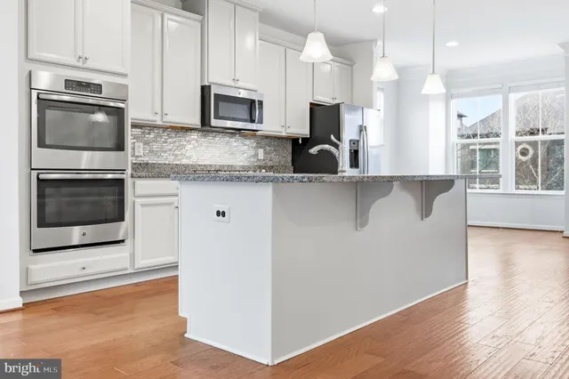a kitchen with granite countertop white cabinets and stainless steel appliances