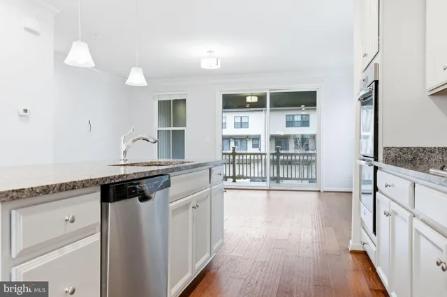 an empty room with wooden floor and kitchen view