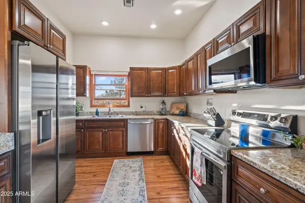 a kitchen with stainless steel appliances granite countertop a stove a sink and a refrigerator