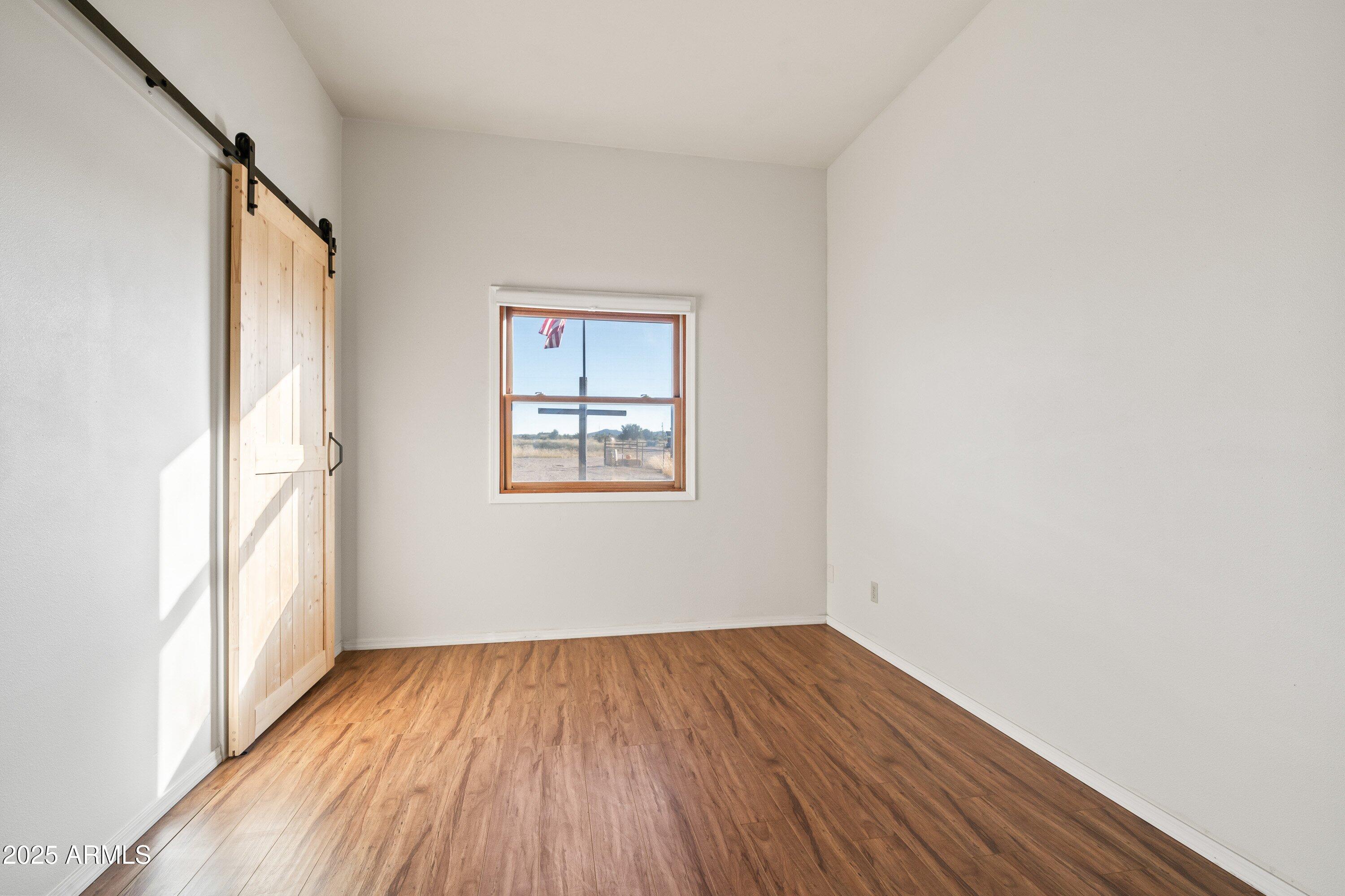 105 Los Encinos Road Sonoita, AZ 85637 - Photo 23 of 39 an empty room with wooden floor and windows