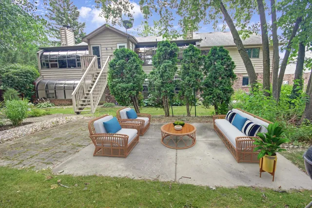 a view of a backyard with table and chairs potted plants and a large tree