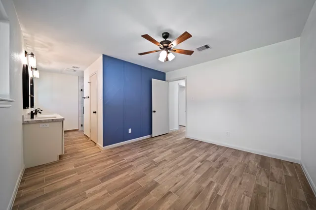 a view of a livingroom with a chandelier fan and wooden floor